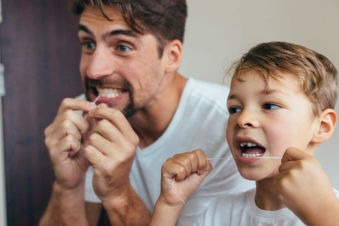 Far og sønn som bruker tanntråd.