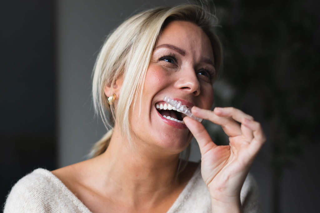Dame med tannreguleringsskinner også kalt usynlig tannregulering