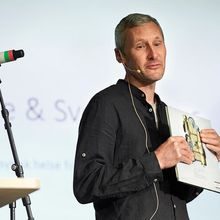 Jonas Bjerketvedt med bok i hånda på en scene