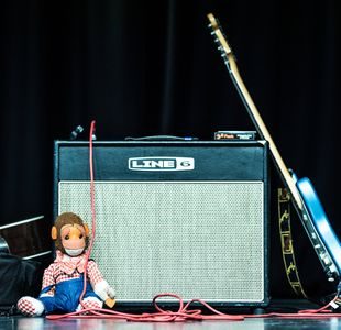 En gitar og en dukke som lener seg mot en forsterker