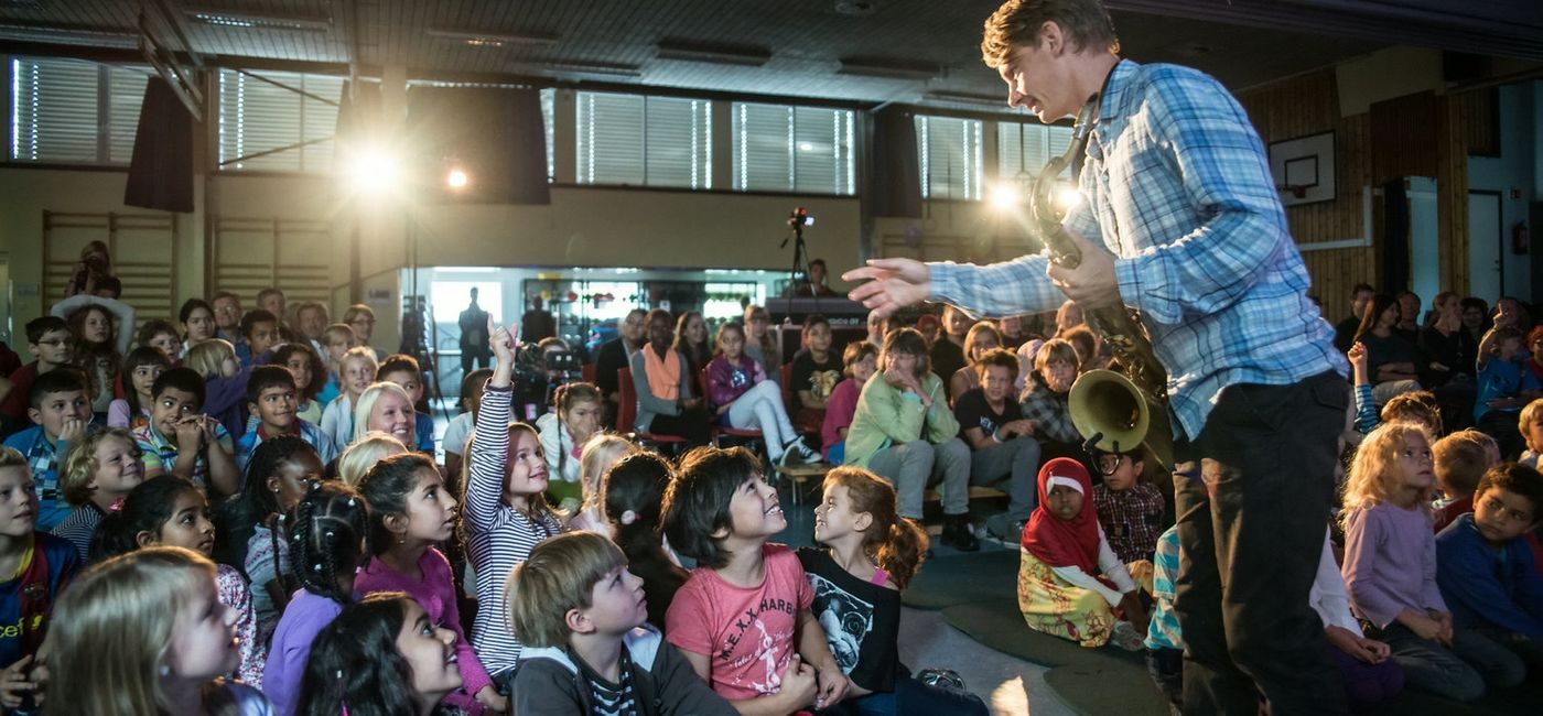 Engasjerte barn stiller spørsmål til saksofonist