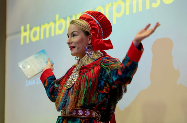 Den samiske forfatteren Saia Stueng står på scenen med armene i været