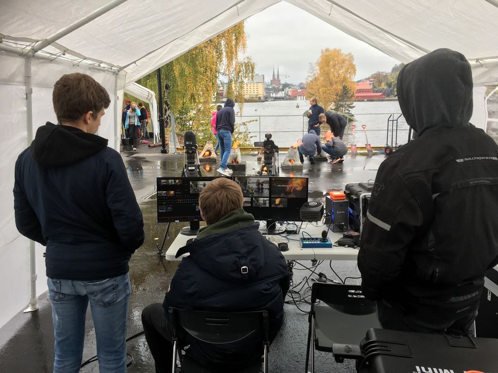 Tre gutter følger med bak monitor mens andre elever filmes i en park
