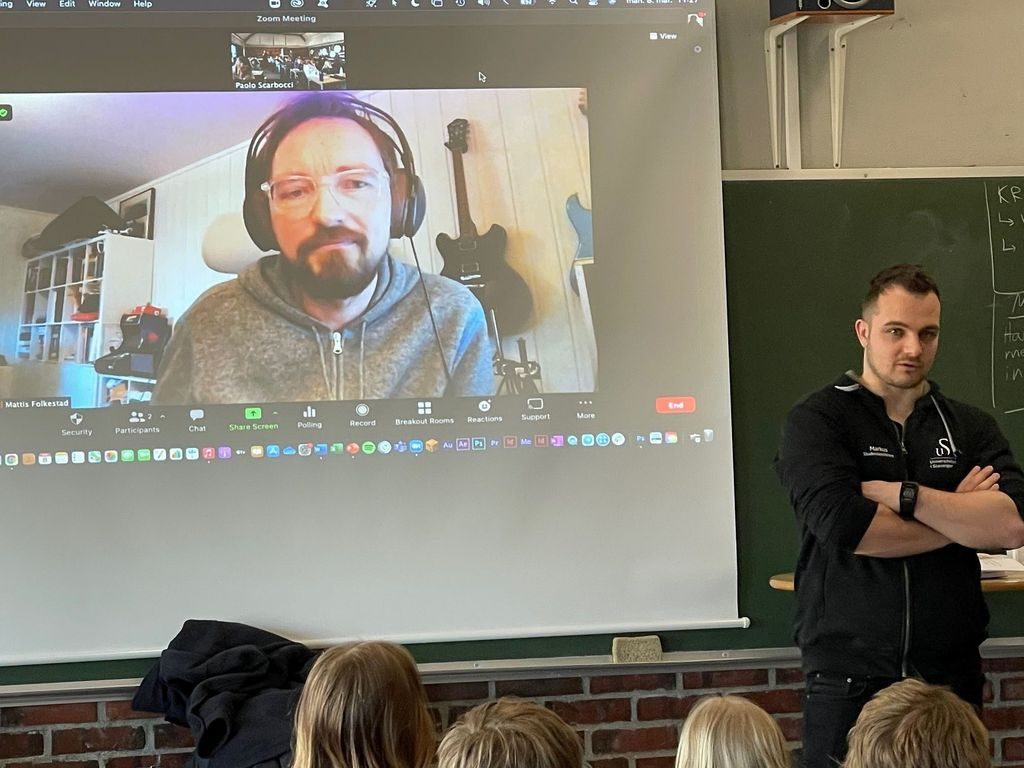 Mattis Folkestad på storskjerm i klasserommet, via Zoom.