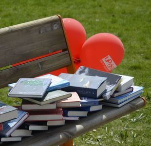 bøker på en benk med røde ballonger bak