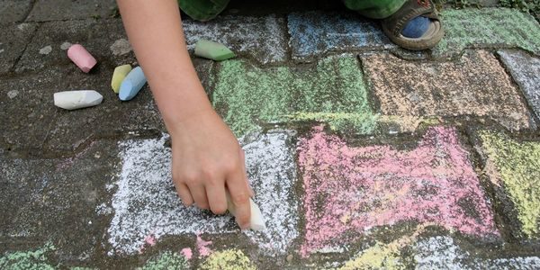 Barn tegner med kritt på asfalten.