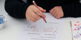 Et barn skriver med brun tusj på et ark.
