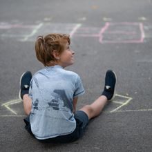 En ung gutt sitter på bakken og smiler