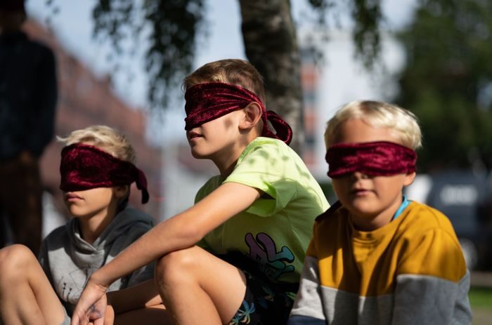 Tre unge gutter med rødt bind for øynene