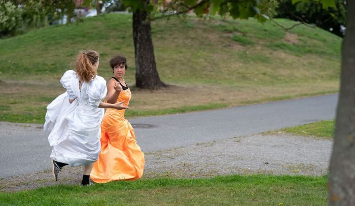 To kvinner i kjole løper på en gressplen