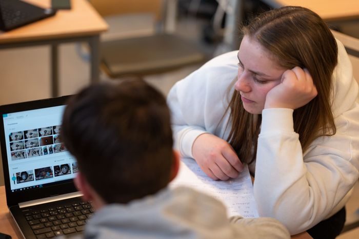 En elev lener seg for å se på skjermen til en annen elev