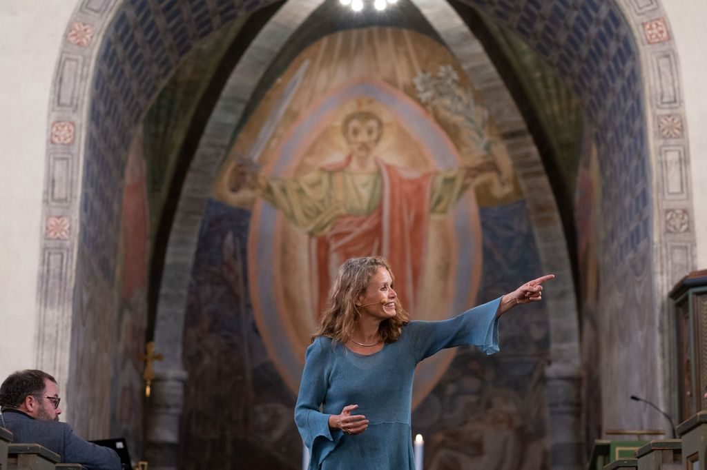 en dame peker til høyre i en kirke