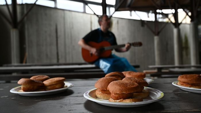 en mann sitter i bakgrunnen med en gitar foran et bord med fiskekaker i brød