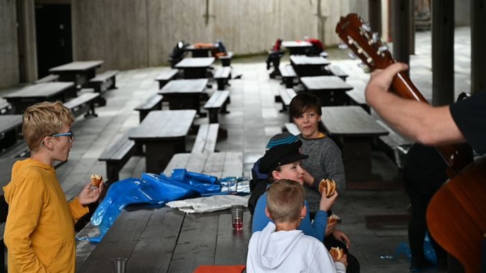 en mann spiller gitar mens fire elever spiser fiskekaker