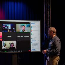 En mann ser på en skjerm hvor man kan se fire andre i et digitalt møte