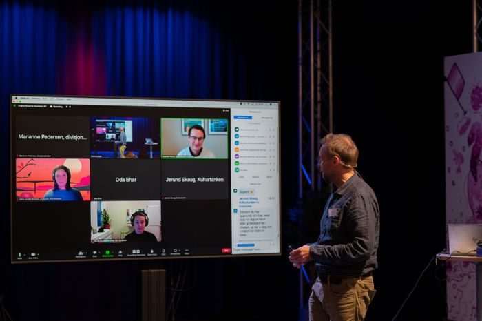 En mann ser på en skjerm hvor man kan se fire andre i et digitalt møte
