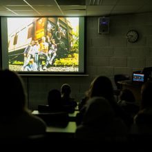 Stillbilde fra filmen "Togrøvere", med en ungdomsgjeng foran en togvogn, vises på skjerm i auditorium.