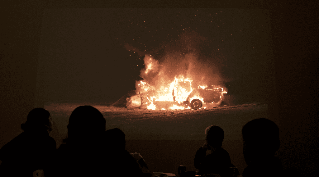 Stillbildet fra filmen "Voice" - Ungdommer ser på film av en bil som brenner
