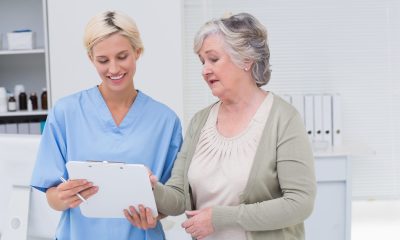 Kvinnelig sykepleier kommuniserer med eldre, kvinnelig pasient.
