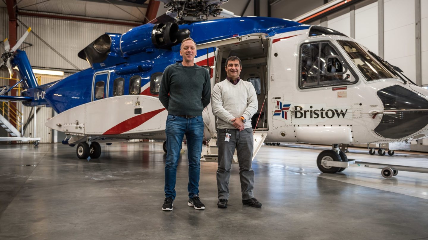 Trond Jacobsen og Furat Gebory står foran et helikopter i en hangar.