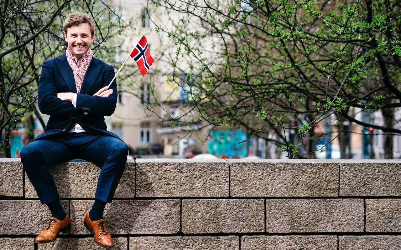 Mangfold: Blid mann sitter på en mur med norsk flagg i hånden.