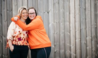 IA-bedrift: To blide kvinner foran en vegg, den ene holder omkring den andre.