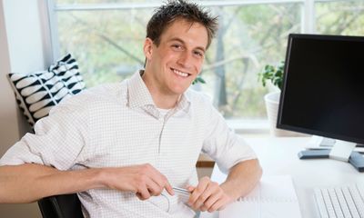 Utfordringer: Blid mann sitter ved et arbeidsbord med PC.