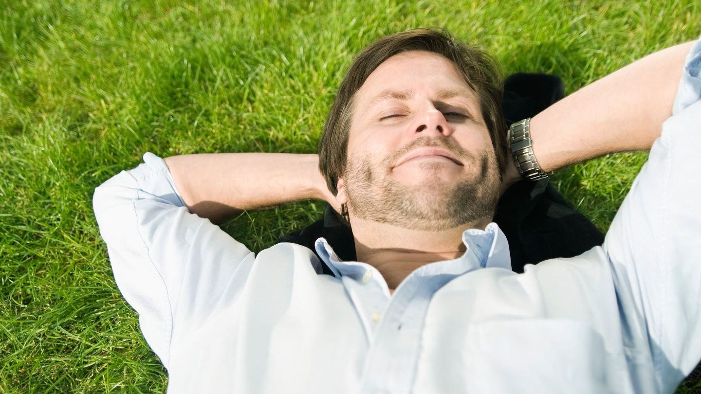 Pauser: Mann ligger i gresset og slapper av.