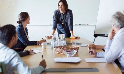 Endringene: En kvinne står foran noen kolleger og snakker ved et bord.
