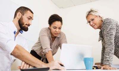 Læring: To kvinner og en mann jobber sammen over en laptop.