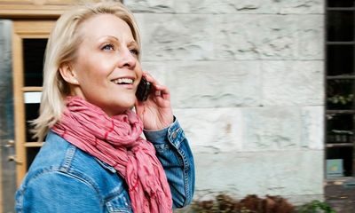 Fleksibel: Blid kvinne snakker i telefonen utendørs.