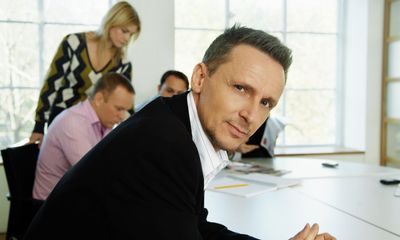 Engasjement: Mann sitter i forgrunnen ved et møtebord, kolleger i bakgrunnen.