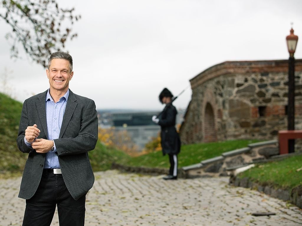 Forsvaret: Smilende mann står ute på Akershus Festning med en gardist i bakgrunnen.