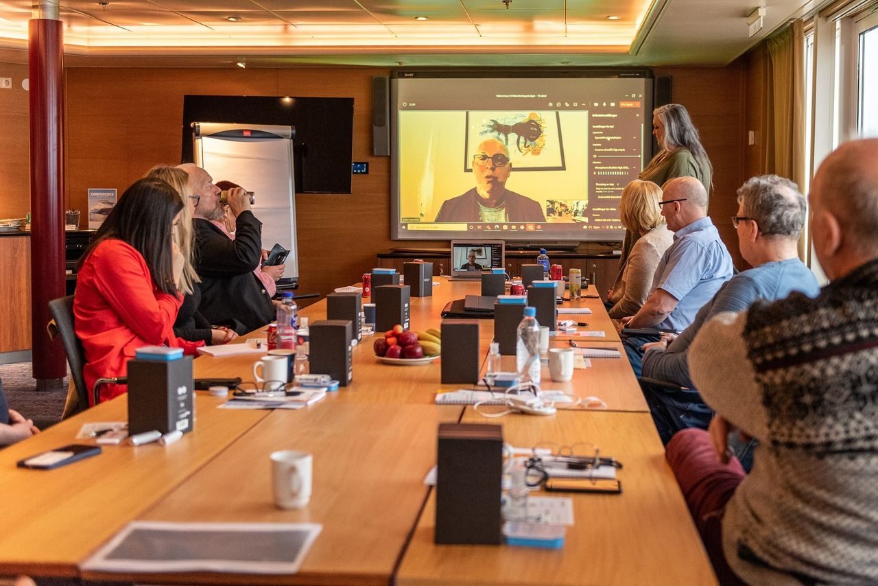 Rekrutteringsansvarlige rundt et bord. De hører på forbundsleder Audun Ingvartsen over videooverføring.