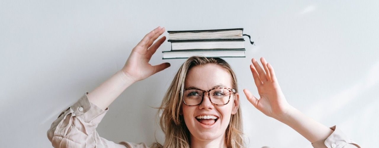 Ung kvinnelig leder med en bunke bøker på hodet