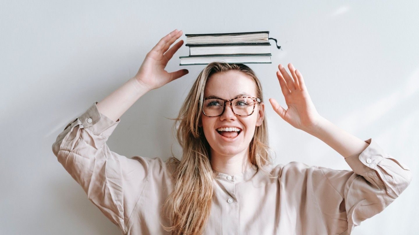 Ung kvinnelig leder med en bunke bøker på hodet