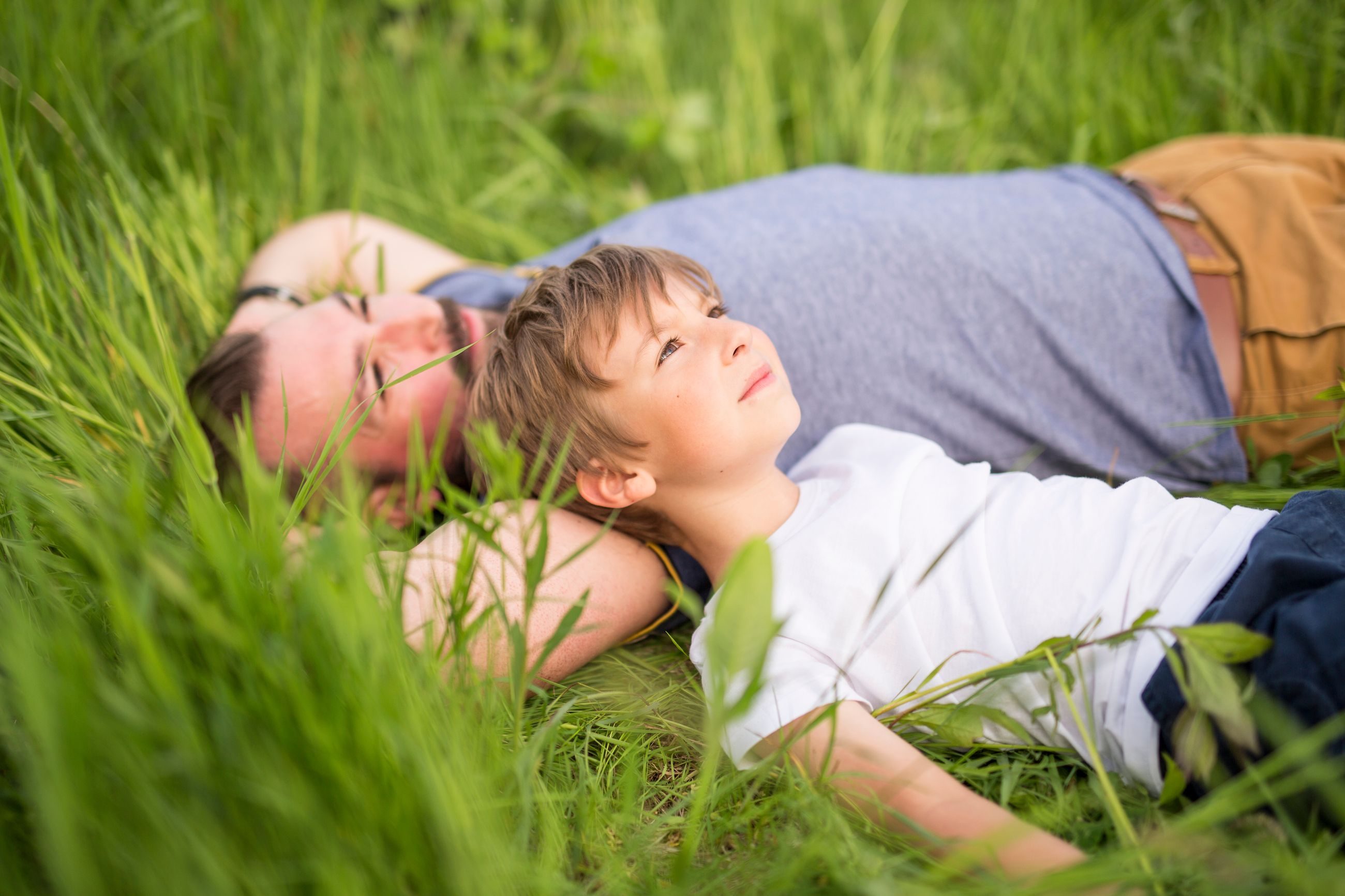 Far og sønn som deler et fint øyeblikk i gresset.