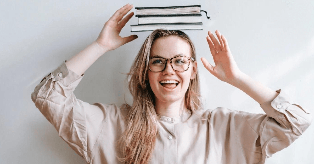 Smilende kvinne med bøker på hodet