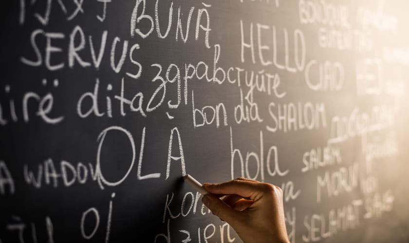 Illustrasjonsfoto av en tavle med ordet "hei" skrevet på flere ulike språk. Foto: Istock.