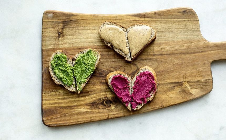 Brødskiver skåret og lagt slik at de ser ut som hjerter med pesto, rødbetehummus og mandelsmør