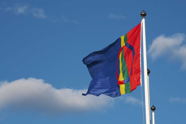 Samernas flagga vajar i vinden mot en blå himmel.