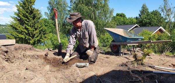 Arkeolog Ola George gräver i jorden med en murslev