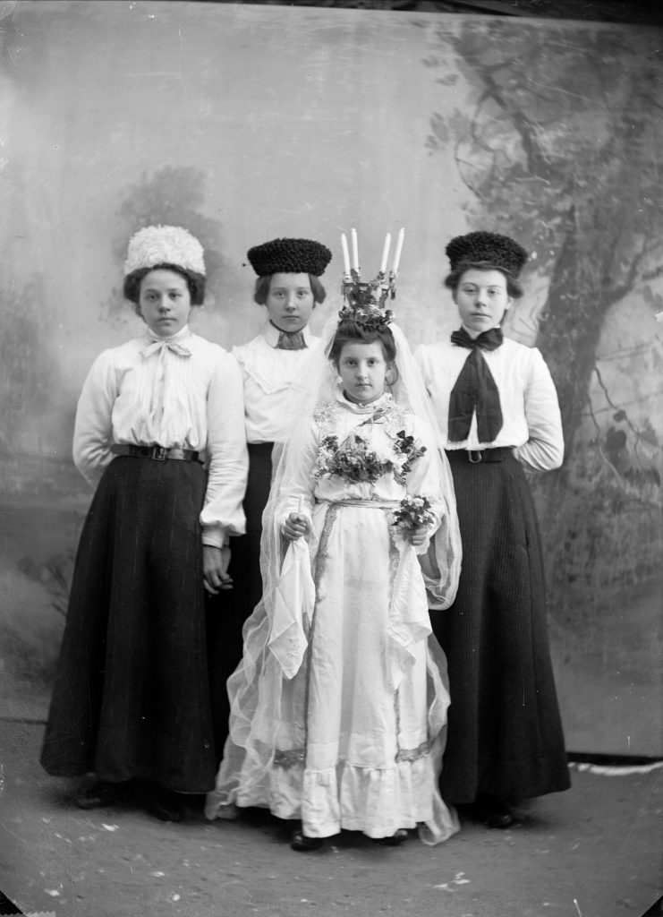 Ett luciafölje med tre kvinnor. 