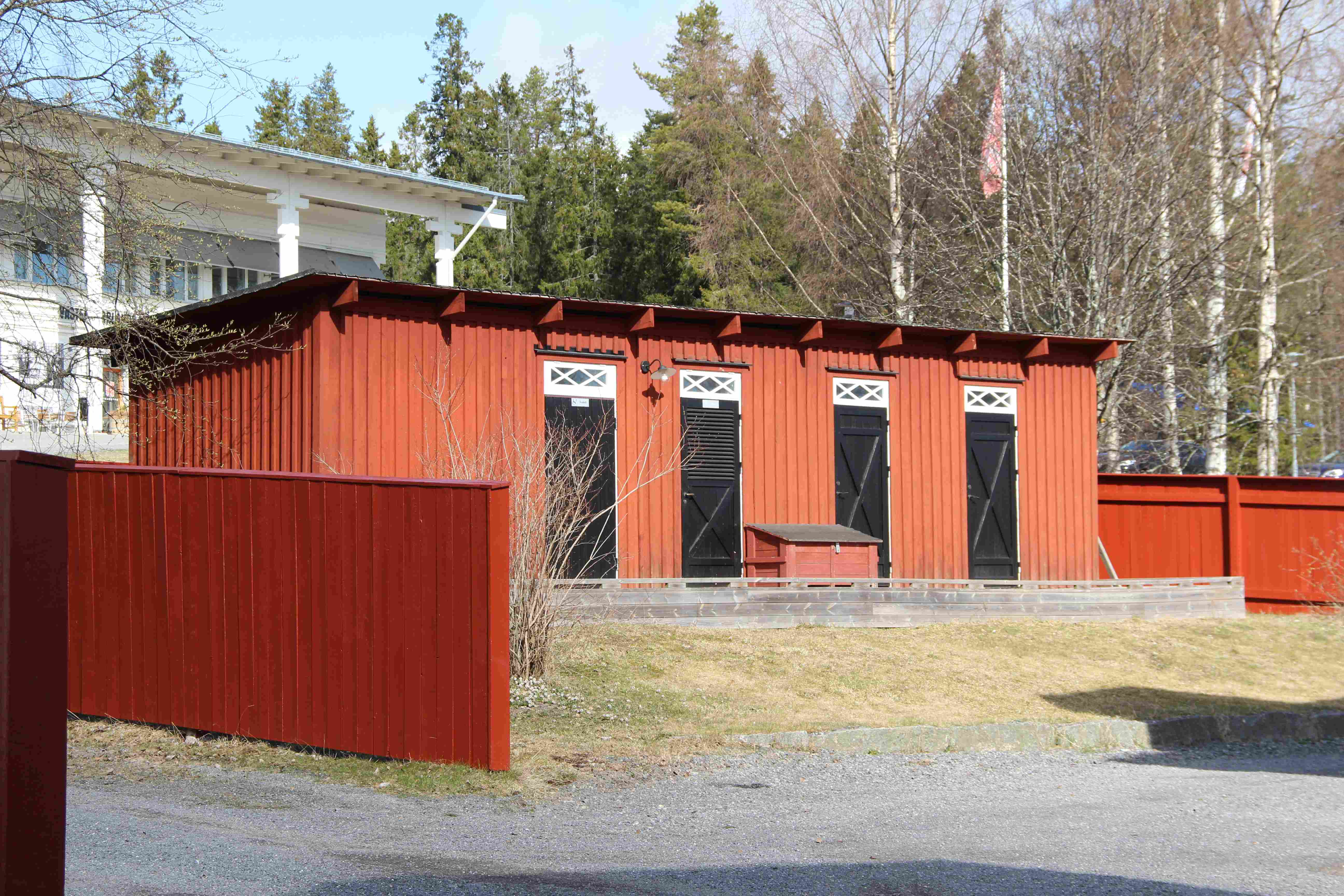 Dasslängan bakom Hellströmska huset är en rödmålad byggnad med fyra svarta dörrar med vita överljus. Taket är ett pappklätt pulpettak. Byggnaden omges av röda plank. I bakgrunden skymtar museibyggnaden.