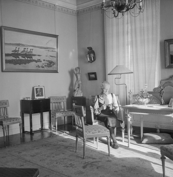 en kvinna sitter i en stol i ett soligt rum.