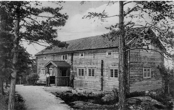 en svartvit bild på ett gammalt timmerhus