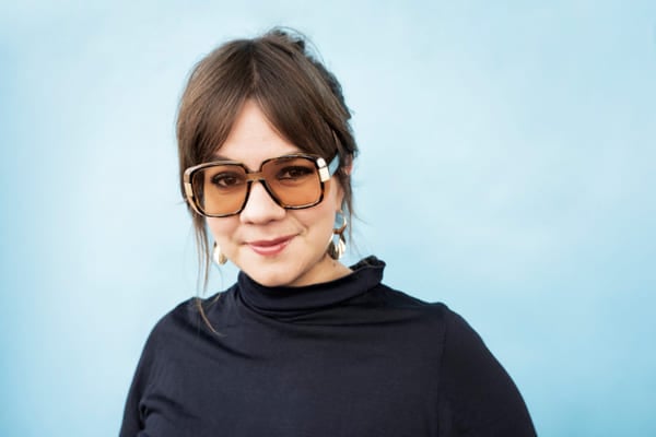 En bild på en kvinna i svart tröja och tonade glasögon. 