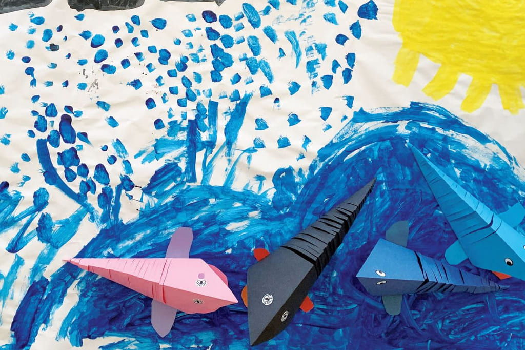 Barnteckning, vatten, so, pappersfigurer som liknar fiskar i blått, svart och rosa